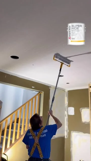 Working on a ceiling above a stairwell.
