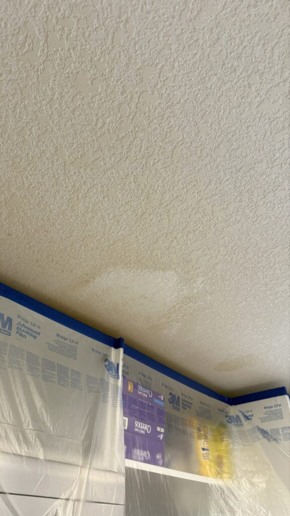Ceiling repair with knockdown texture preparation, showing protective masking and surface patching by Chamos Texturing.
